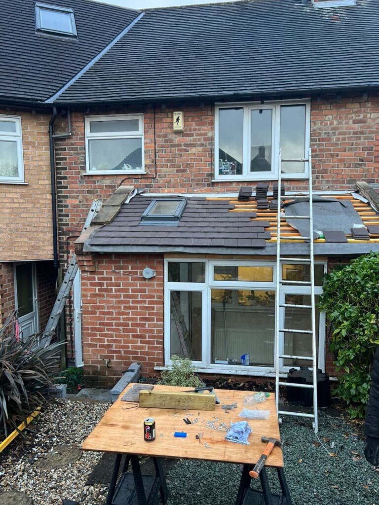 This is a photo of a roof extension that is having new roof tiles installed. This is a photo taken from the roof ridge looking down a tiled pitched roof on to a flat roof. Works carried out by Gainsborough Roofing Repairs